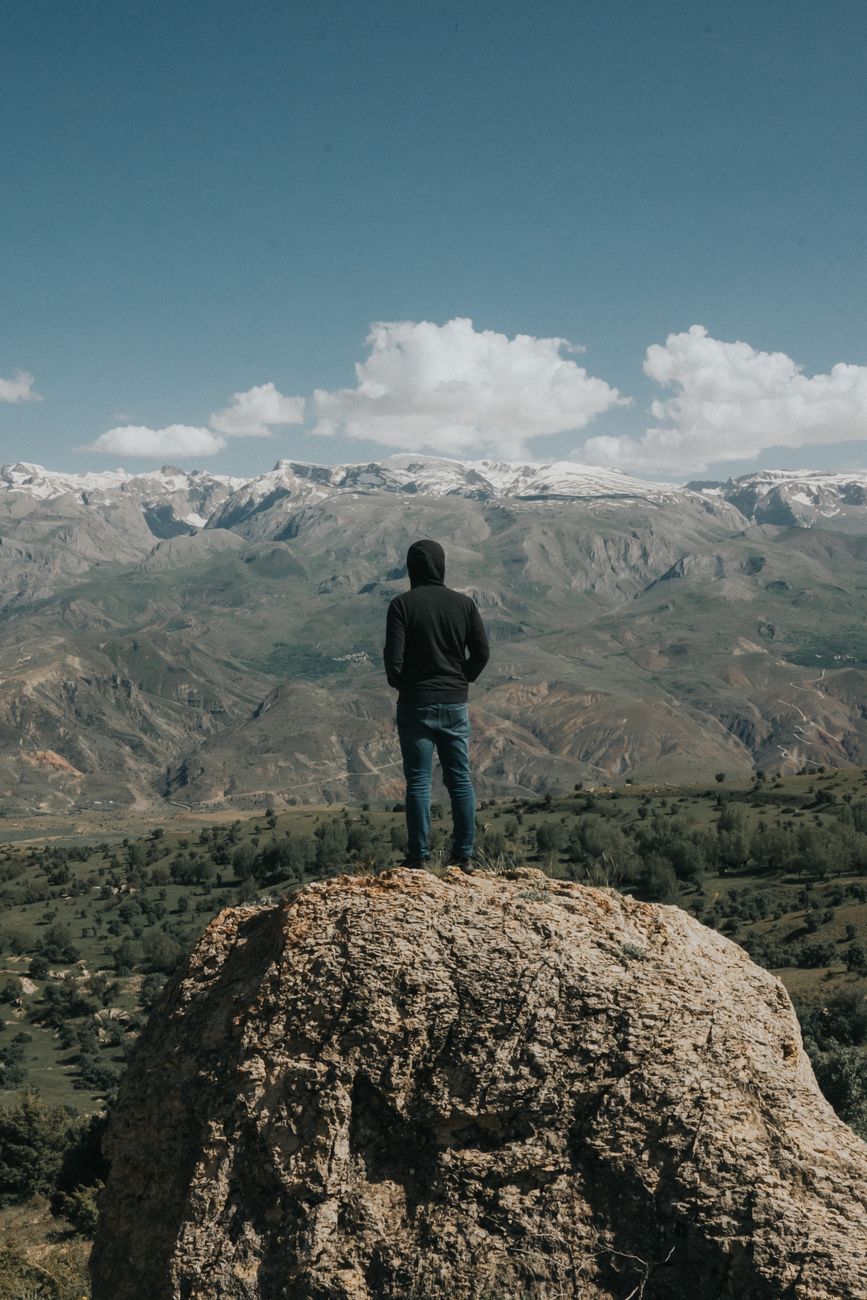 Travel journal author standing overlooking mountain valleys
